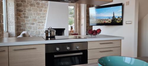 cocina con fogones y TV en la pared en Πέτρα, Ελιά και Λεβάντα, en Tolo