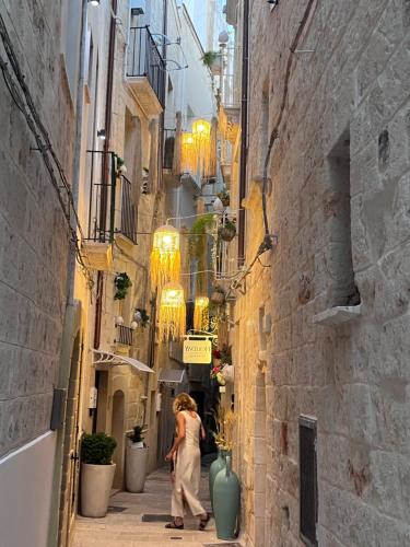 una mujer caminando por un callejón estrecho con edificios en Guest House 38 Monopoli, en Monopoli