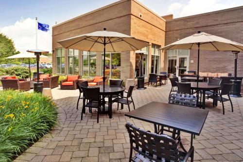 um pátio exterior com mesas, cadeiras e guarda-sóis em Hilton Garden Inn Lake Forest Mettawa em Lake Forest