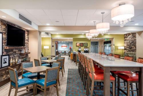 un restaurant avec un long bar avec des chaises et des tables dans l'établissement Hampton Inn Baltimore Bayview Campus, à Baltimore