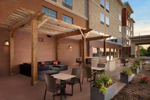 un patio con mesas y sillas frente a un edificio en Homewood Suites By Hilton Kansas City Speedway, en Kansas City