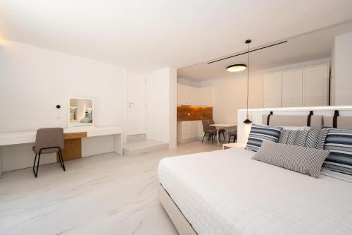 a white bedroom with a bed and a desk at Arcs Suites & Residences in Mýkonos City