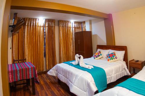 a bedroom with two beds with towels on them at Hostal Mirador Korichaska in Puno