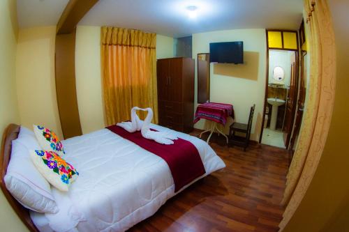 a bedroom with a large white bed with bows on it at Hostal Mirador Korichaska in Puno