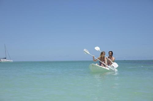 three people on a paddle board in the water at Royal Palm Beachcomber Luxury in Grand Baie