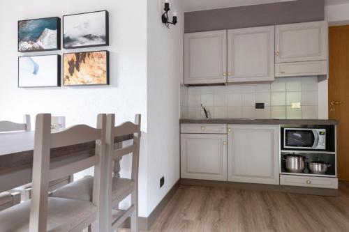 une cuisine avec des placards blancs et une table de cuisine dans l'établissement Chalet Vedig, à Santa Caterina di Valfurva