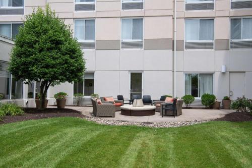 un patio avec des chaises et un arbre en face d'un bâtiment dans l'établissement Hilton Garden Inn BWI Airport, à Linthicum