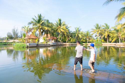 ケガにあるKega Lighthouse Resort Bình Thuậnの男と男の子が水中に立っている