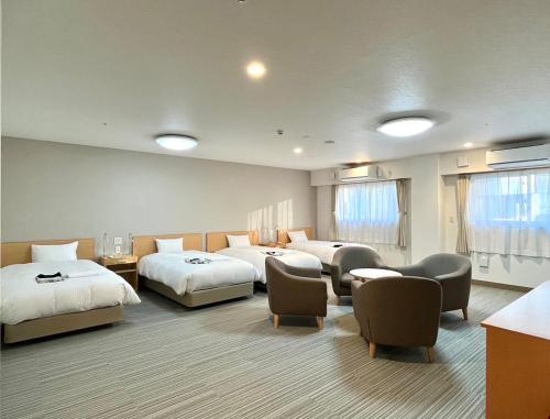 een hotelkamer met drie bedden en stoelen bij Sun Plaza Hotel Fuji Lake Yamanaka in Yamanakako