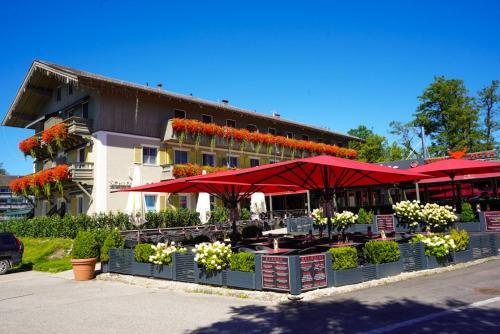 Hotel Schlossblick Chiemsee في برين أم كيمزيه: مطعم فيه مظلات حمراء امام مبنى