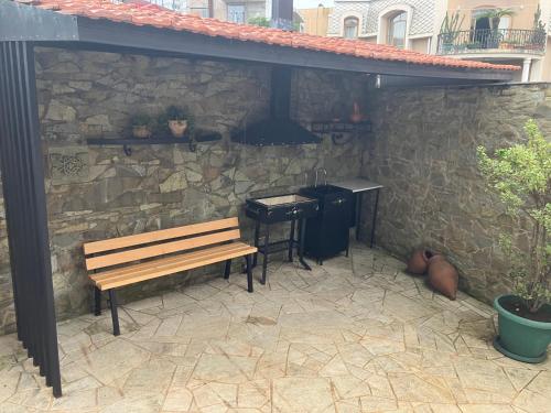 una panchina sotto un muro di pietra con un grill di Villa Old Batumi a Batumi