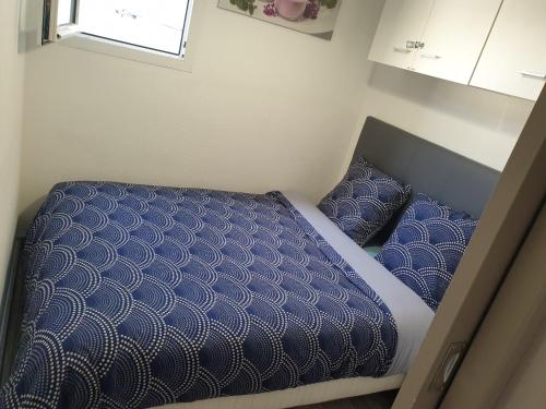 una piccola camera da letto con letto con piumone e cuscini blu di Appartement vacances cap d’agde a Cap d'Agde