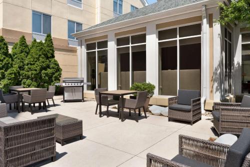 eine Terrasse mit Stühlen, Tischen und einem Grill in der Unterkunft Hilton Garden Inn Fort Wayne in Fort Wayne