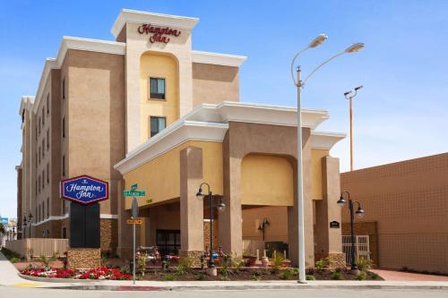 ein Hotelgebäude mit einem Schild davor in der Unterkunft Hampton Inn Los Angeles Int'l Airport/Hawthorne in Los Angeles