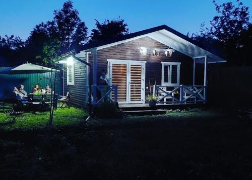 a small house with people sitting in the yard at night at Садиба Герасімових in Kamianets-Podilskyi