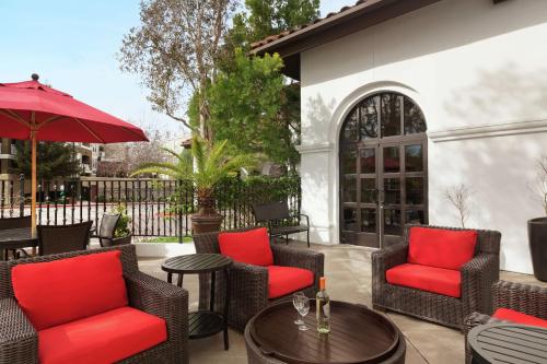 eine Terrasse mit Stühlen, einem Tisch und einem Sonnenschirm in der Unterkunft Hilton Garden Inn Cupertino in Cupertino