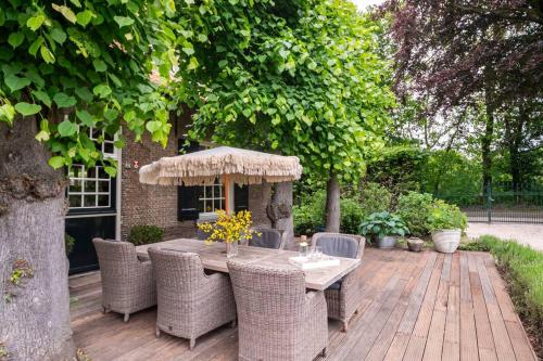 una mesa con sillas y una sombrilla en una terraza de madera en Filion's Place, en Roosendaal