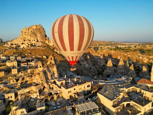 Ein Heißluftballon fliegt über eine Stadt in der Unterkunft Ages in Cappadocia in Uchisar