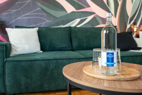 een fles water op een tafel naast een groene bank bij LE Vacation 3-Room-Apartment 67qm, Küche, Netflix, Free-TV in Schkeuditz