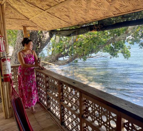 une femme debout sur un balcon donnant sur l'eau dans l'établissement Borbon's Treehouse By the Sea, à Mambajao