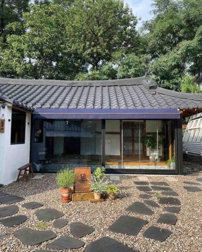 uma casa com um telhado roxo e algumas plantas em Bow Hanok House em Gangneung