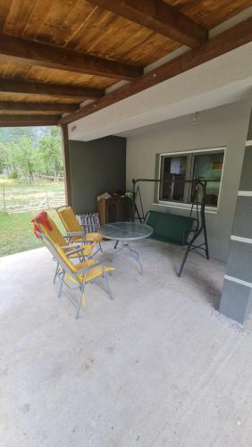 een patio met stoelen, een tafel en een raam bij Vila MM Boračko jezero in Konjic