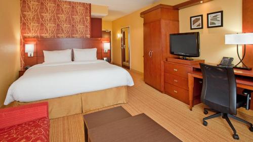 um quarto com uma cama, uma secretária e uma televisão em Courtyard by Marriott Pittsburgh North/Cranberry Woods em Cranberry Township