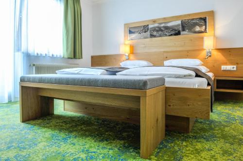 ein Schlafzimmer mit einem großen Holzbett in einem Zimmer in der Unterkunft Alpinhotel Maistatt in Schladming