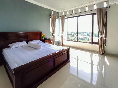 RedDoorz @ Green Homestay Syariah Baubau في Baubau: غرفة نوم بسرير كبير ونافذة كبيرة