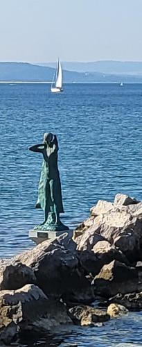 una estatua de un murciélago en el agua con un velero en small miramare appartamento sogno sul mare, en Trieste