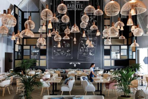 a dining room with tables and chairs and chandeliers at Hilton Garden Inn Paris La Villette in Paris