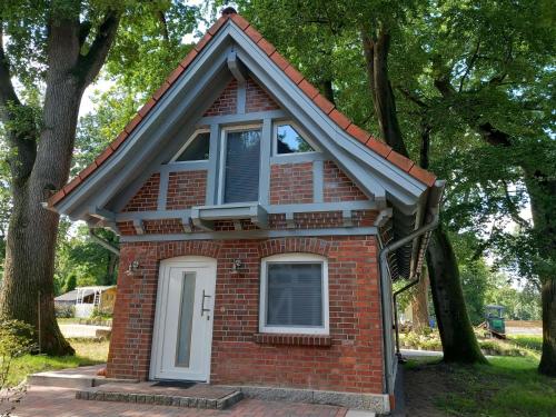 een klein rood bakstenen huis met een raam bij Ferienhaus Heidenest, E-Bike, Bettwäsche und Handtücher zubuchbar in Buchholz in der Nordheide