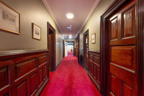 a hallway with wooden doors and a red carpet at Palmers Lodge Swiss Cottage in London