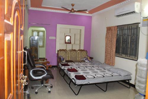 ein Zimmer mit einem Bett und einem Stuhl darin in der Unterkunft Centaurus Homestay near Trichy Airport in Tiruchchirāppalli