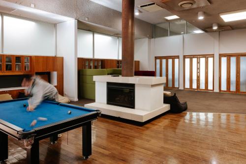 Ein Mann spielt Billard in einem Zimmer mit Kamin in der Unterkunft Canberra Accommodation Centre in Canberra