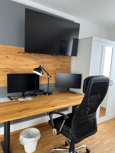 a computer desk with two monitors and a chair at New Age Boardinghaus Bad Wimpfen in Bad Wimpfen