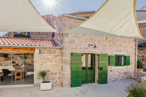 uma casa de pedra com portas e janelas verdes em Villa Teza Hvar em Hvar