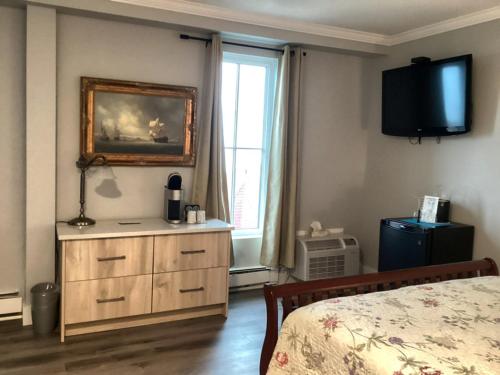 a bedroom with a bed and a dresser and a window at Lunenburg Arms Hotel in Lunenburg