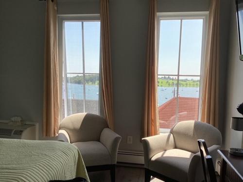 a bedroom with two chairs and a bed and windows at Lunenburg Arms Hotel in Lunenburg