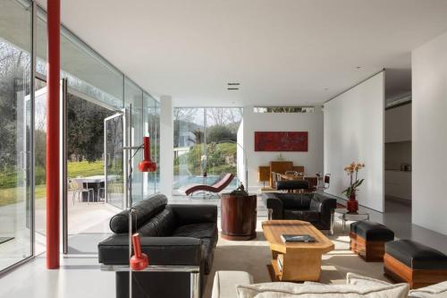 a living room with black leather furniture and glass walls at Casa Briteiros in Guimarães