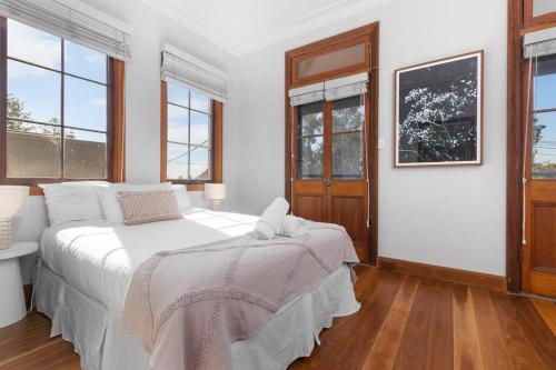 Dormitorio blanco con cama y ventanas en Classic Elegance on The Hill, en Newcastle