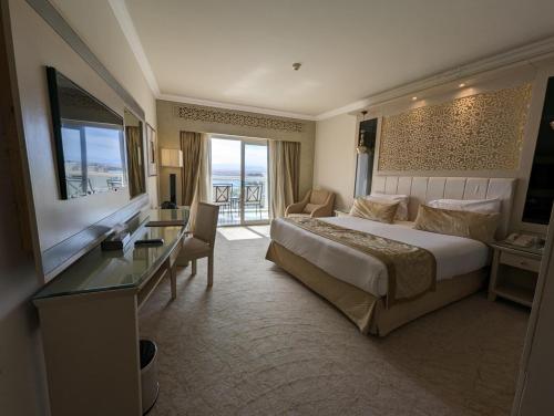 een hotelkamer met een groot bed en een bureau bij KaiSol Romance Resort Sahl Hasheesh - Adults Only in Hurghada