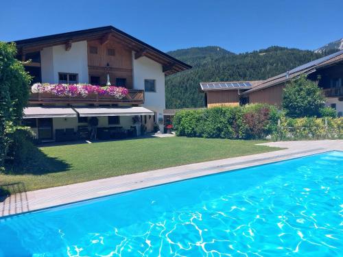 a villa with a swimming pool in front of a house at Appartement Unterbering in Söll