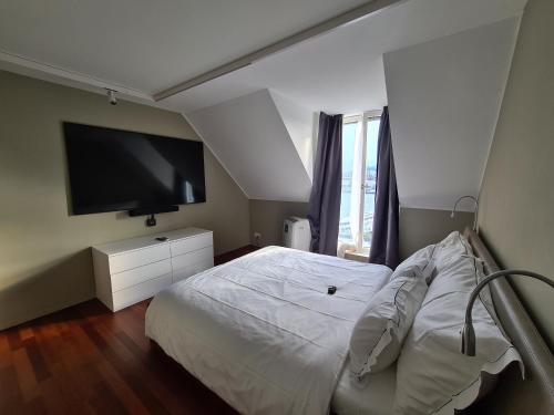 1 dormitorio con 1 cama blanca y TV de pantalla plana en Lucerne Lake View Apartments, en Lucerna