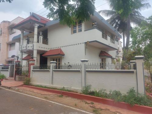 una casa blanca con una valla delante en SAN HOME STAY, en Mysore