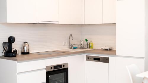 a white kitchen with white cabinets and a sink at Golden Apartment in Skopje