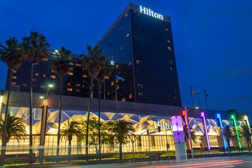 um hotel Hilton à noite com palmeiras em frente em Hilton Los Angeles Airport em Los Angeles