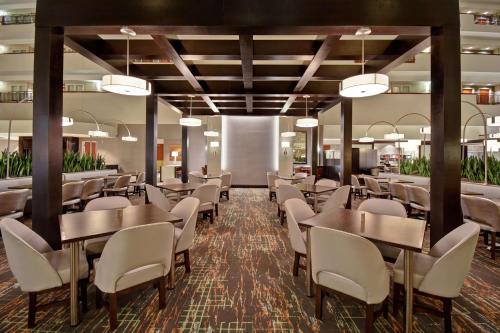 un comedor con mesas y sillas blancas en Embassy Suites Little Rock, en Little Rock