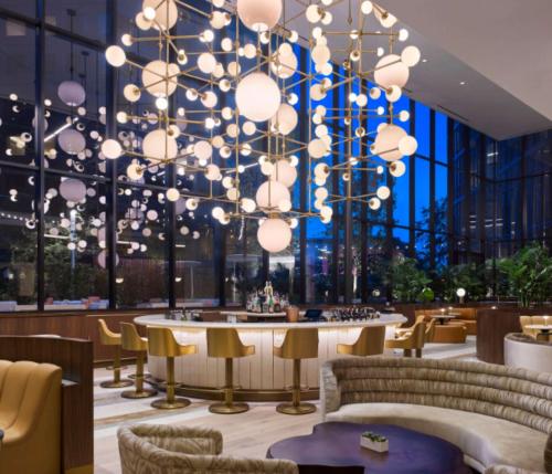 un ristorante con un grande lampadario a braccio, tavoli e sedie di C. Baldwin, Curio Collection by Hilton a Houston