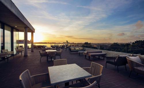 patio ze stołami i krzesłami oraz zachodem słońca w obiekcie Boeira Garden Hotel Porto Gaia, Curio Collection by Hilton w mieście Vila Nova de Gaia